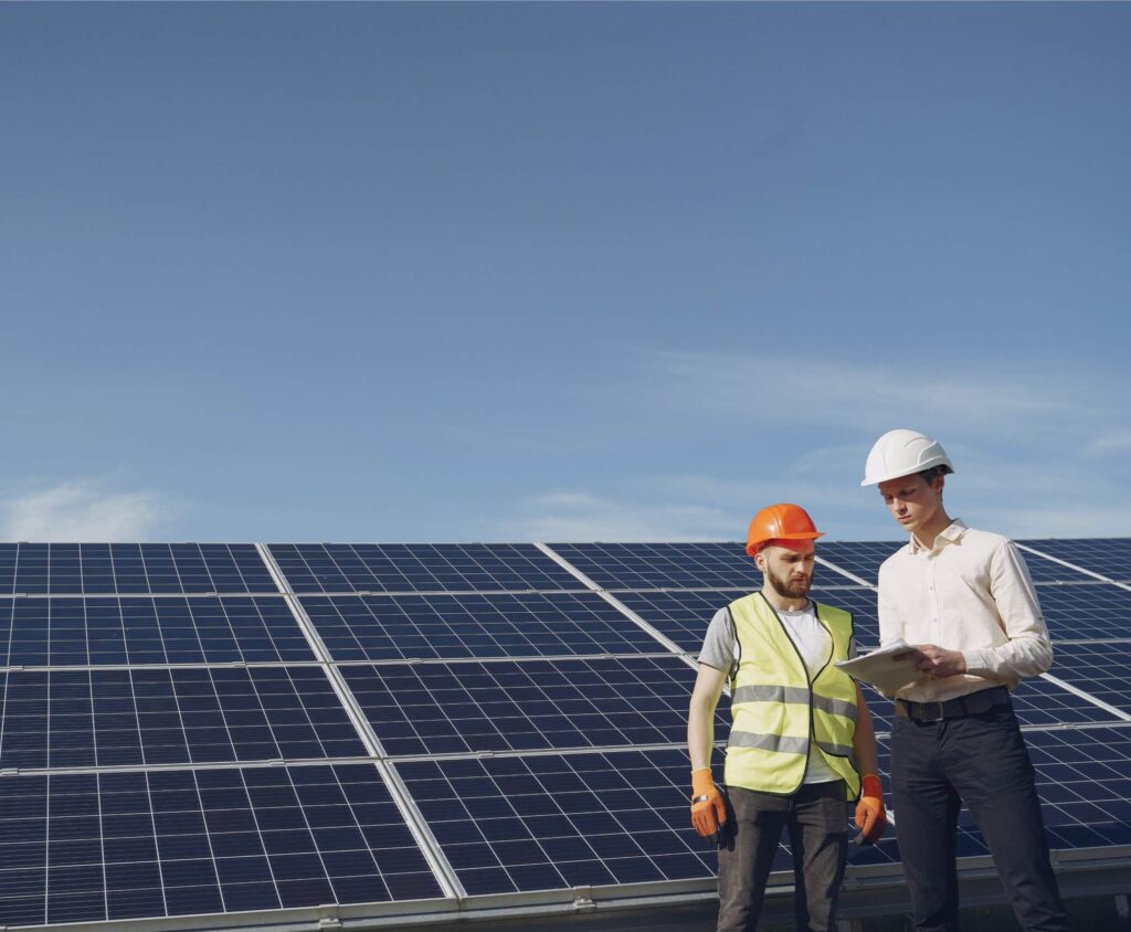 Zwei Planer stehen vor einer PV-Anlage und besprechen Gewerbespeicher
